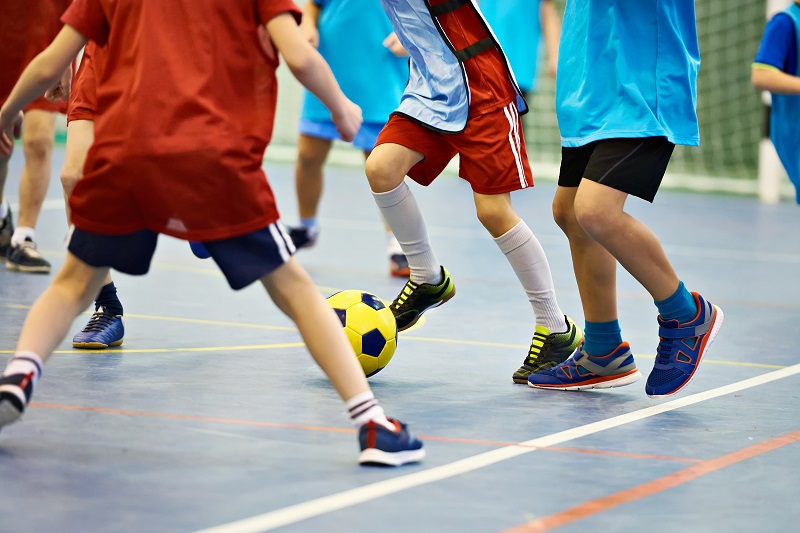 children playing soccer in indoors with yellow football